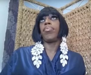 Jasmine Masters wearing a royal blue robe and rolling her eyes during her filming of her famous "And I Oop" video.