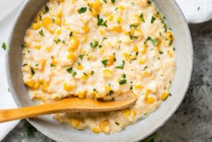A warm bowl of rich creamed corn, complete with serving spoon