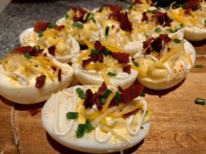 A close-up of turkey bacon deviled eggs, garnished beautifully with chives and cayenne pepper