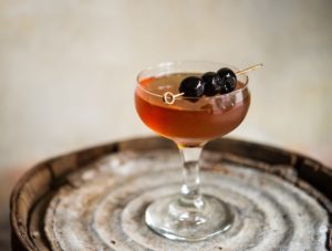 A Manhattan cocktail, garnished with a luxardo cherry