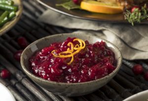 A tangy cranberry sauce topped with a lemon garnish, placed near the Thanksgiving turkey