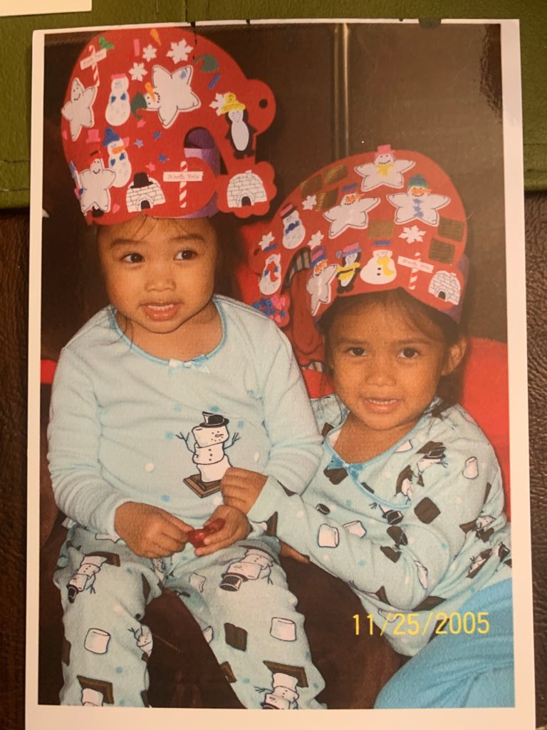 Two young girls wear matching S'mores Snowman pajamas and Christmas hats