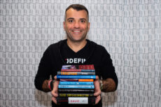 JohnHart CEO holding a stack of 9 great books to read in 2020, with the titles of each book visible