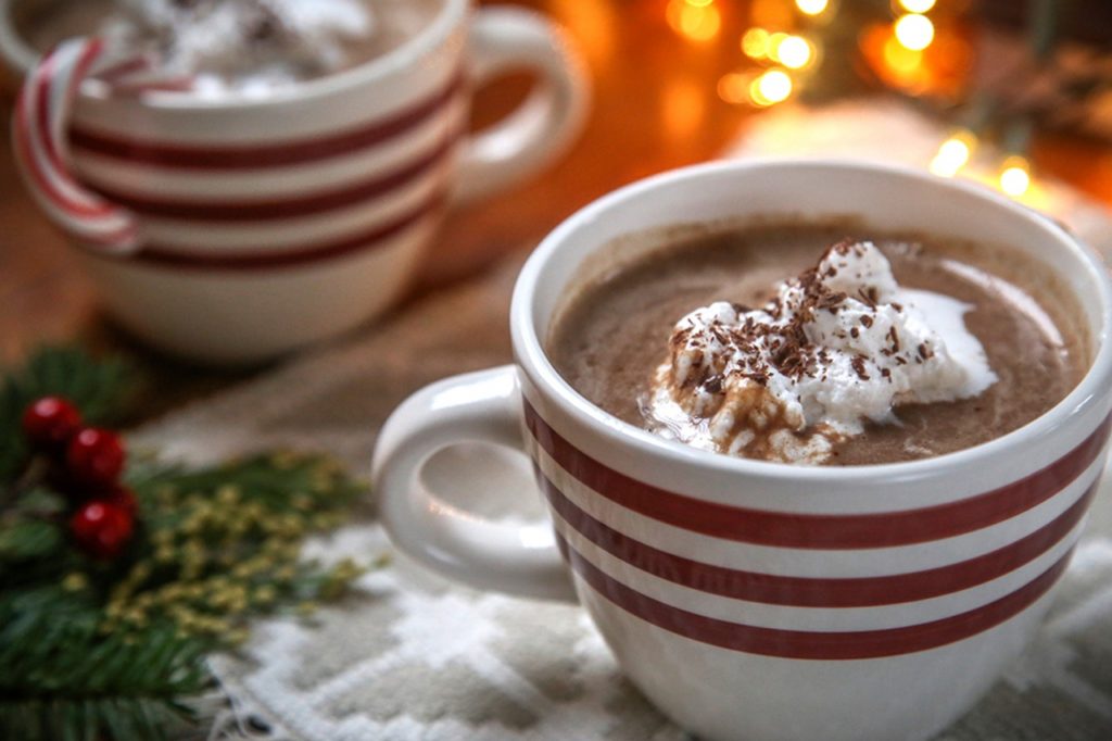Two piping hot cups of delicious, rich hot chocolate, placed on top of a festively decorated table