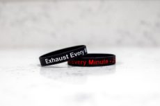 Exhaust Every Minute wristbands, one with red text, one with white text