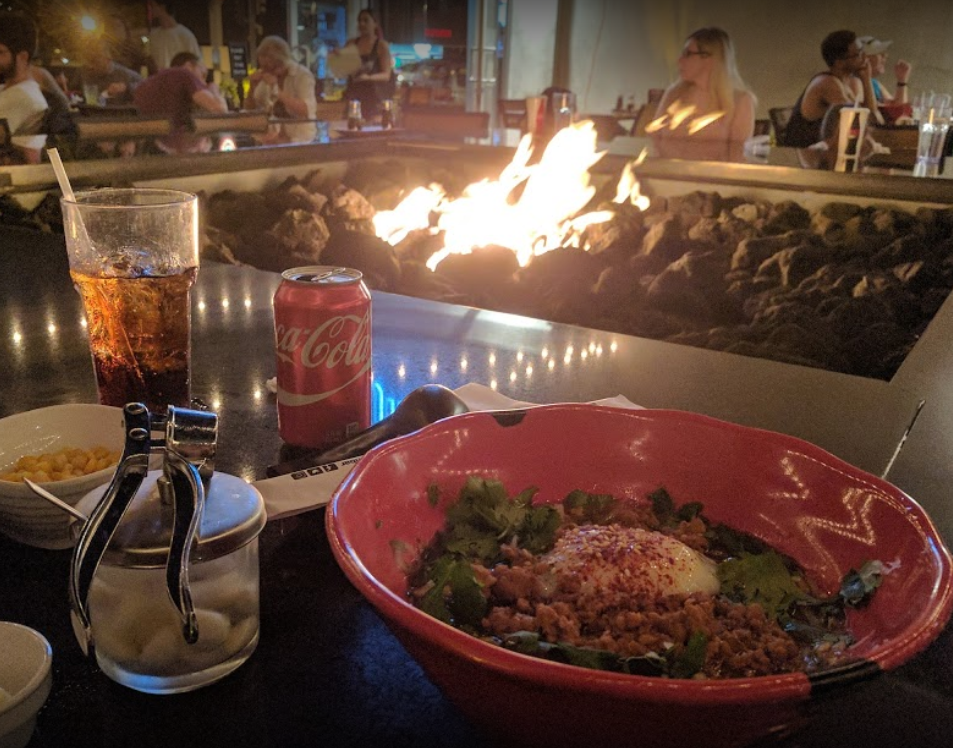 jinya large outdoor fireplace bar with a bowl of food and a coke glass and can chop sticks fire blazing people sitting around eating