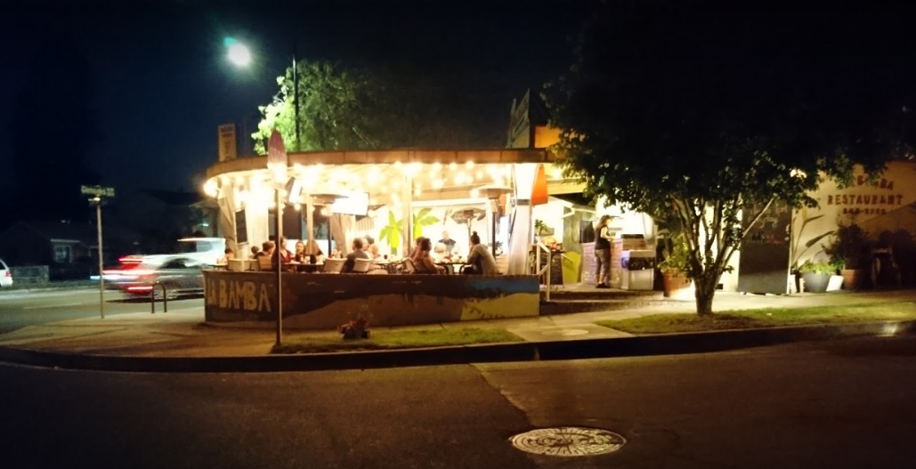 la bamba restaurant outside patio light up at night with people eating there tree and street view 