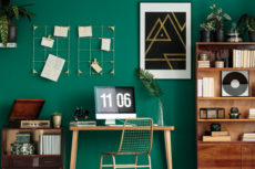 Green home office interior with a computer on the desk, wooden cabinet and poster on the wall