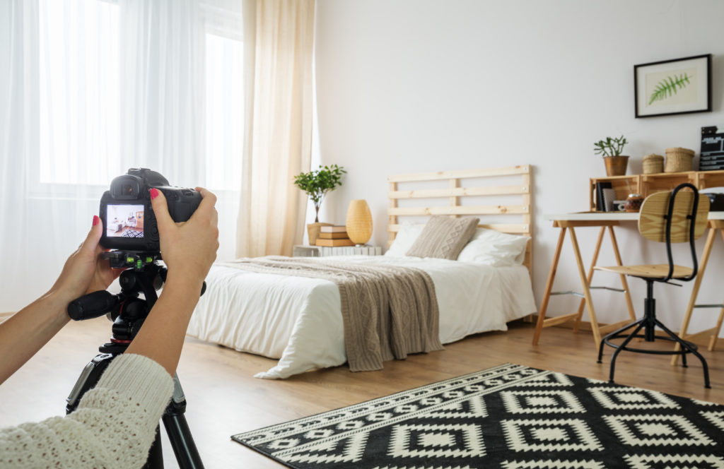 A person with a camera taking real estate photos of a bedroom
