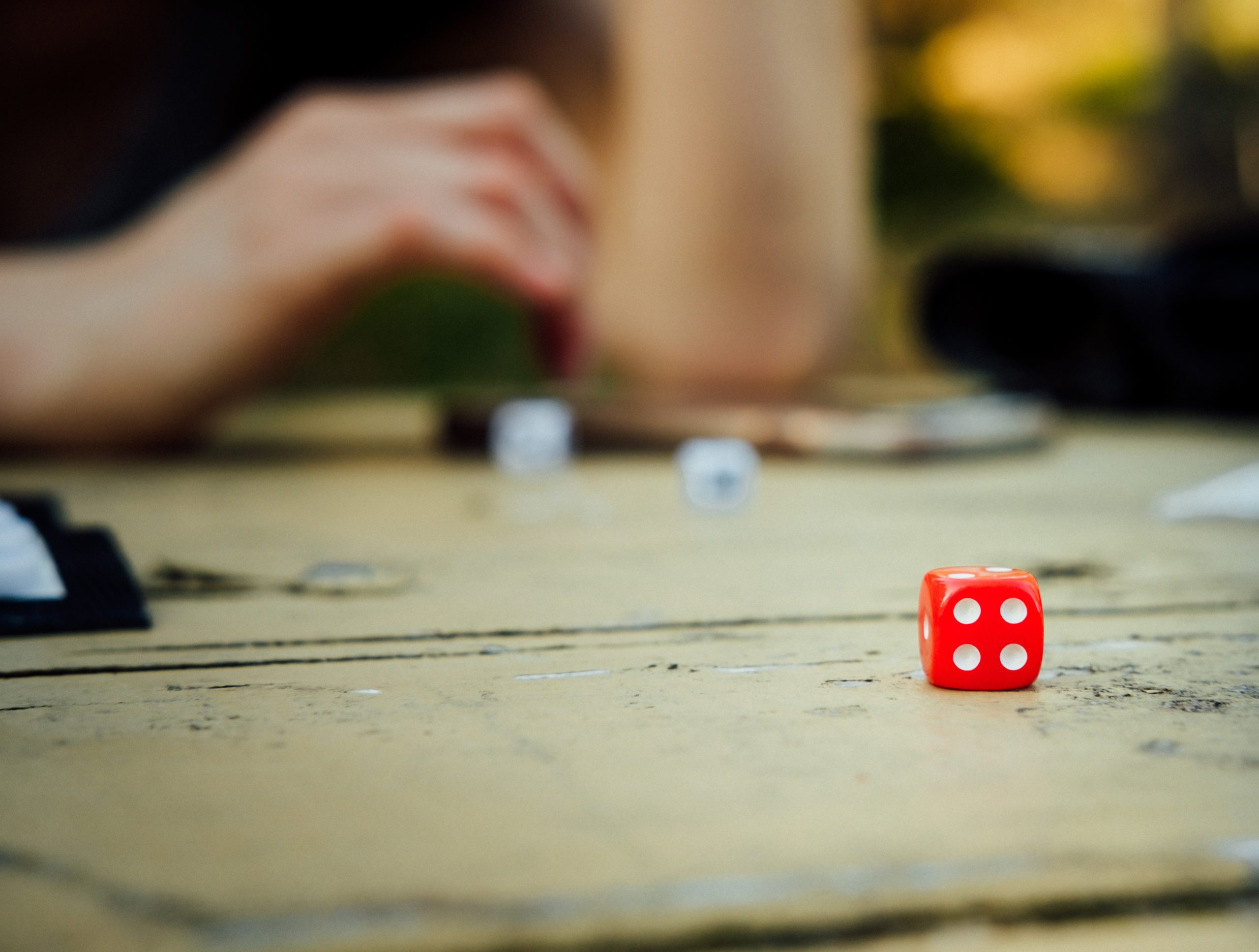 Person focusing on playing a board game and red dice