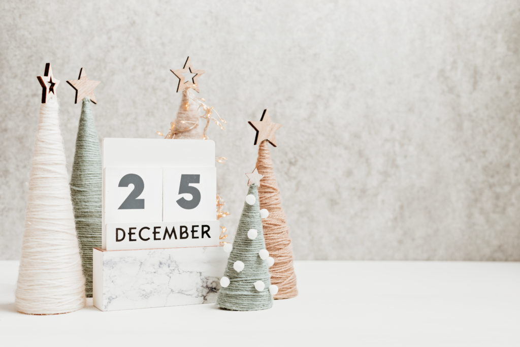 Christmas craft background with calendar and handmade yarn cone xmas trees in natural colors.  DIY organic sustainable christmas decoration
