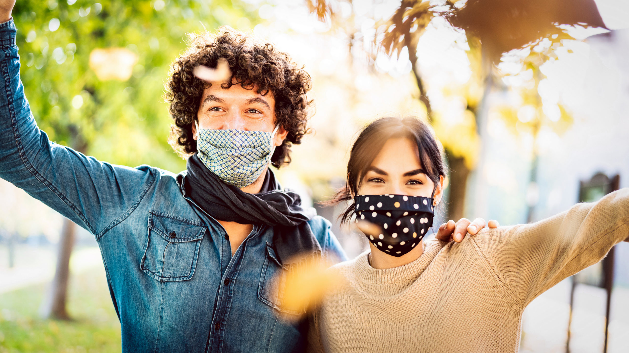 Happy couple of lovers enjoying autumn travel time outdoor wearing protective mask - New normal love concept with boyfriend and girlfriend having fun together