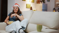 girl on couch watching best christmas comedy movies
