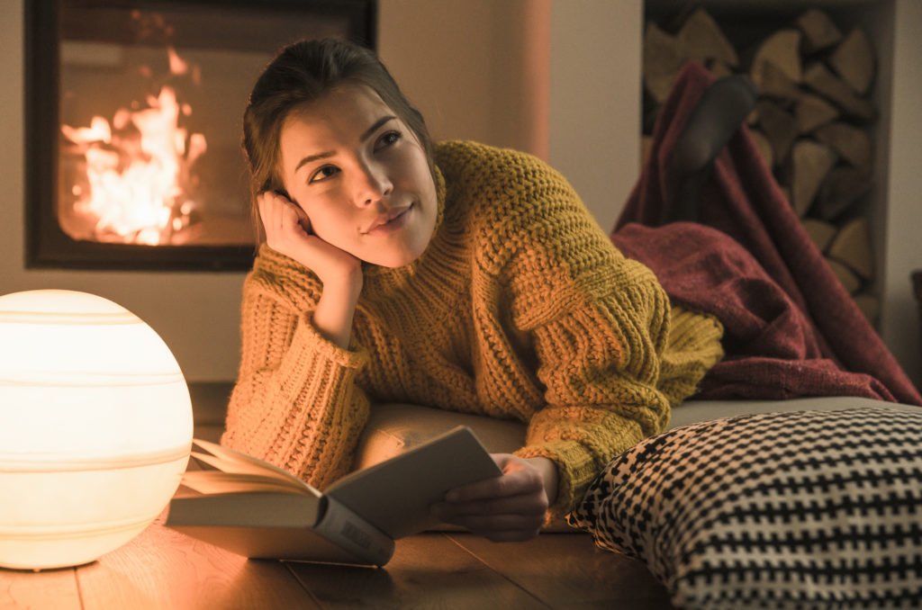 young woman reading book by fireplace adhering to california building code