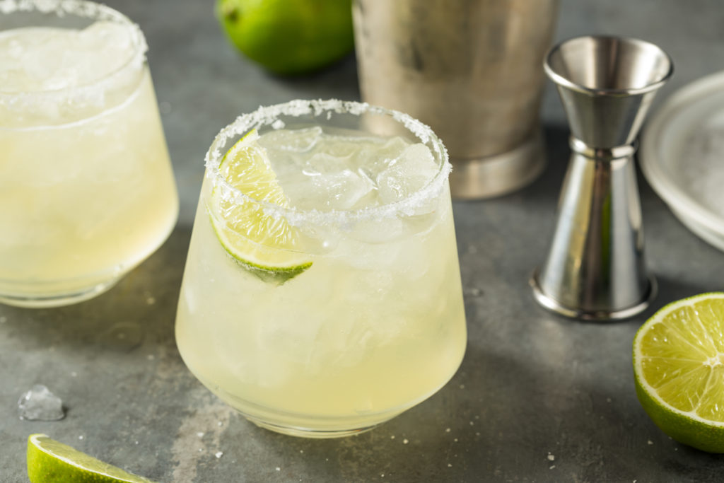 classic lime margarita with shaker and lime wedge.