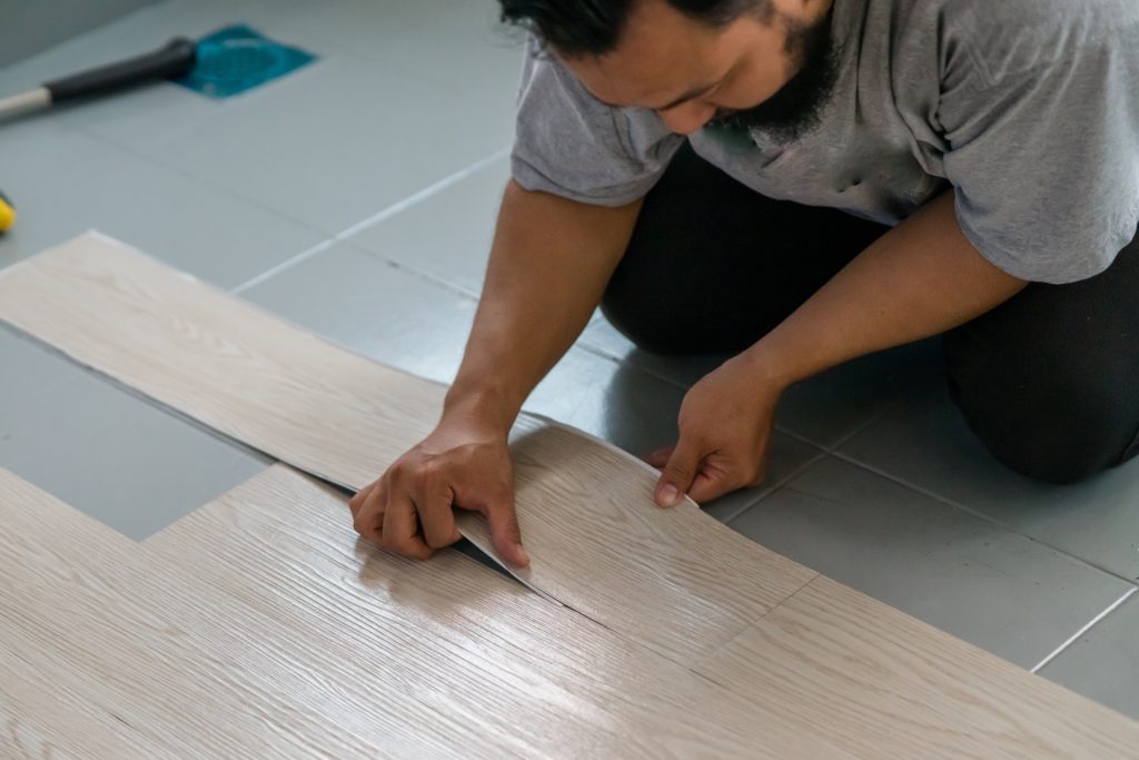 man placing peel and stick flooring over tile