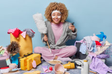 Smiling young woman surrounded by various spring cleaning items