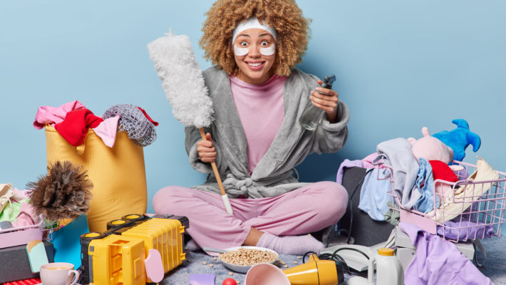Smiling young woman surrounded by various spring cleaning items
